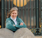 Debbie Wells posing on a rock in front of a fence